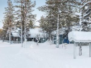 a snow covered yard with a sign in front of trees at Holiday Home Keromaja by Interhome in Kakslauttanen