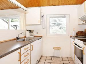 cocina con armarios blancos, fregadero y taburete en 12 person holiday home in Sp ttrup, en Ålbæk