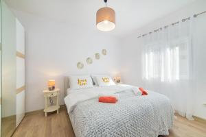 a white bedroom with a white bed with orange pillows at Apartment Karlo - Grad Ploče, Croatia in Ploče