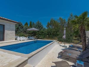 basen z krzesłami i parasolem na dziedzińcu w obiekcie Holiday Home Villa Joy by Interhome w mieście Novigrad