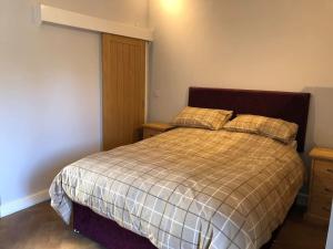 een slaapkamer met een bed met een geruite deken en kussens bij The Dairy, Wolds Way Holiday Cottages, 1 bed studio in Cottingham