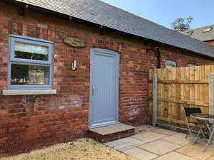 een bakstenen huis met een blauwe deur en een patio bij The Dairy, Wolds Way Holiday Cottages, 1 bed studio in Cottingham