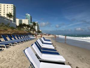 una fila de tumbonas azules y blancas en una playa en Hide House, en Hollywood