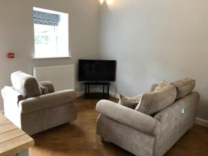 a living room with two chairs and a television at The Milking Parlour, Wolds Way Holiday Cottages, 1 bed cottage in Cottingham