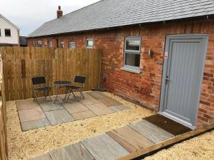 a patio with chairs and a table in front of a building at The Milking Parlour, Wolds Way Holiday Cottages, 1 bed cottage in Cottingham