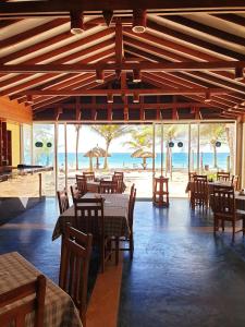 a restaurant with tables and chairs and the beach at Oasey Ayurveda Hotel in Bentota