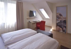 a hotel room with a bed and a red chair at Hotel - Restaurant Hirsch in Heimsheim