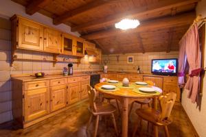 uma cozinha com uma mesa de madeira com cadeiras e uma televisão em Apartment Paradise em Livigno
