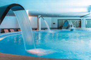 a woman in a swimming pool with a water slide at Vila Gale Ampalius in Vilamoura