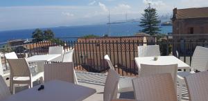 eine Terrasse mit weißen Tischen und Stühlen und Meerblick in der Unterkunft Albergo Milazzo Inn AiMori in Milazzo