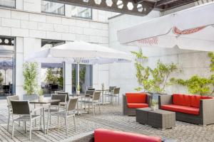 un patio al aire libre con mesas, sillas y sombrillas en IntercityHotel Dresden en Dresden