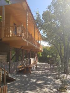 un edificio de madera con terraza y mesas de picnic en Amiran's Lake en Tiflis