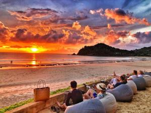 a group of people sitting on the beach watching the sunset at LiLi's Rooms in Ko Lanta