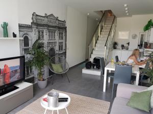 圣朱利安斯Duplex Maisonette with Heated P-Pool and Jacuzzi的带电视的客厅和坐在桌子上的女人