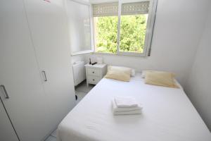 Un dormitorio blanco con una gran cama blanca y una ventana en casa en Masnou junto a playa y tren, en Masnou