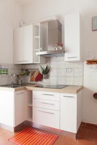 a white kitchen with white cabinets and a red rug at Appartamento 121 in Prato