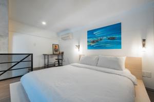a bedroom with a large white bed and a painting on the wall at CIRCADIAN Industrial Loft In Heritage Building in Ho Chi Minh City