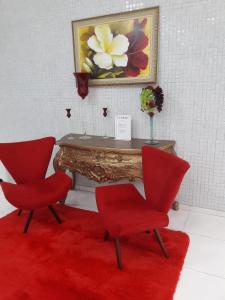 una mesa con 2 sillas rojas y una alfombra roja en Syros Hotel, en Gama