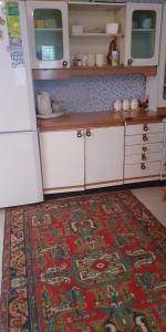 a kitchen with white cabinets and a rug on the floor at Guest House OTILIA in Gyumri
