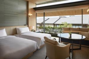 a hotel room with two beds and a table and chairs at Park Hyatt Kyoto in Kyoto