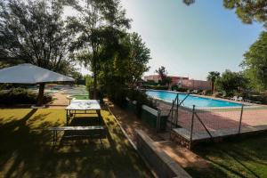 a table with an umbrella next to a tennis court at Hostel Layos, Toledo in Layos