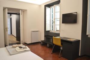 a room with a bed and a desk and a television at Da Domè Charm Rooms in Levanto