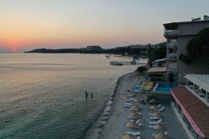 ein Strand mit Sonnenschirmen und das Meer bei Sonnenuntergang in der Unterkunft Melis Hotel Kusadasi in Kusadası