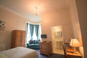 ein Schlafzimmer mit einem Bett, einer blauen Couch und einem Spiegel in der Unterkunft Pinegrove Hotel in Carlisle