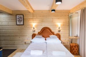 a bedroom with wooden walls and a bed with two pillows at udanypobyt Apartamenty Przy Dolinach C i D in Kościelisko