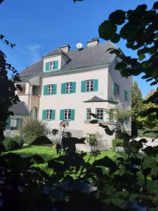 uma grande casa branca com persianas verdes em Villa Leopoldskron em Salzburgo