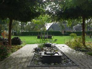 a garden with a stone path and trees and a yard at B&B Achterhoeks Halle in Halle
