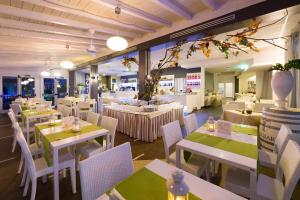 a restaurant with white tables and white chairs at Hotel Mioni Royal San in Montegrotto Terme