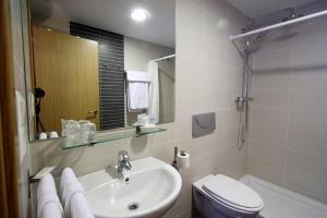 a bathroom with a toilet, sink, mirror and tub at Dormavalencia Hostel in Valencia