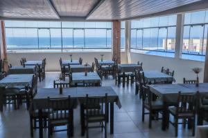a restaurant with tables and chairs and a view of the ocean at Scaini Palace Hotel in Arroio do Silva
