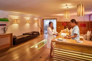 zwei Frauen stehen an einer Theke in einem Raum in der Unterkunft Mountain Hotel Mezdì in Kolfuschg