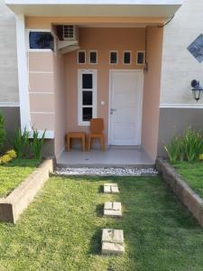 a house with a door and a chair in the grass at Bis homestay in Sumbawa Besar +10 photos