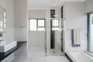 a white bathroom with a shower and a sink at FC14 - Pezula Ocean & Valley Views in Knysna +24 photos