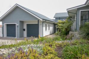 a house with two garage doors in a garden at FC14 - Pezula Ocean & Valley Views in Knysna
