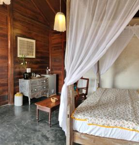a bedroom with a bed and a dresser and a table at The Artist Cottages in Morjim