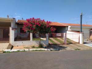 a house with a fence and a tree with pink flowers at Quarto para uma pessoa com banheiro exclusivo in Alfenas