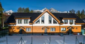 a large house with mountains in the background at Lomnica Garden Apartment in Tatranská Lomnica