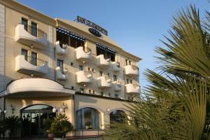 ein Hotelgebäude mit Palmen davor in der Unterkunft Hotel San Clemente in Santarcangelo di Romagna