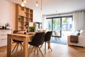 a kitchen and living room with a wooden table and chairs at Lomnica Garden Apartment in Tatranská Lomnica