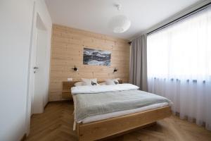 a bedroom with a bed and a wooden wall at Lomnica Garden Apartment in Tatranská Lomnica