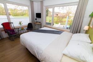 a bedroom with a white bed and a large window at Boutiquehotel B&B the SJinn in Schin op Geul