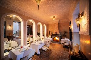 a restaurant with white tables and chairs and a fireplace at Riad Star by Marrakech Riad in Marrakech