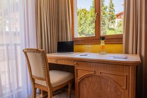 a desk with a laptop and a chair next to a window at Hotel Arte in St. Moritz