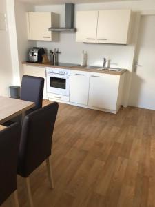 a kitchen with white cabinets and a wooden floor at Kienburg in Matrei in Osttirol