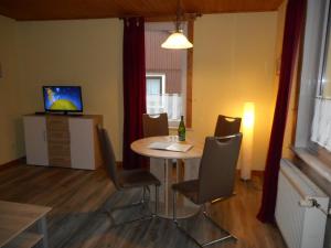 Apartments Carmen-Braunlage في برونلاغ: غرفة بطاولة وكراسي وتلفزيون