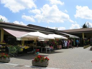 a market with white umbrellas in front of a building at Happy Camp mobile homes in Camping Bella Italia in Peschiera del Garda